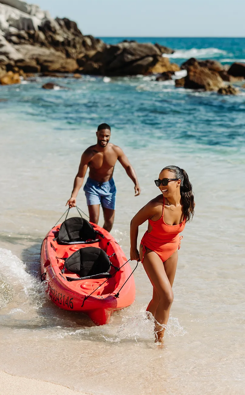 Couple pulling a kayak at the beach in Cabo San Lucas