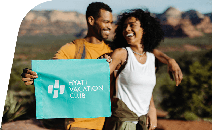 Couple holding a Hyatt Vacation Club flag in the mountains