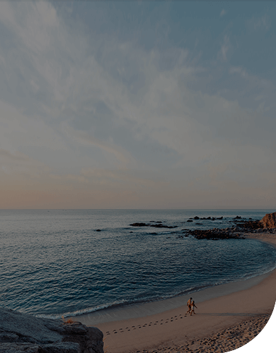 two people in the distance walking on a beach