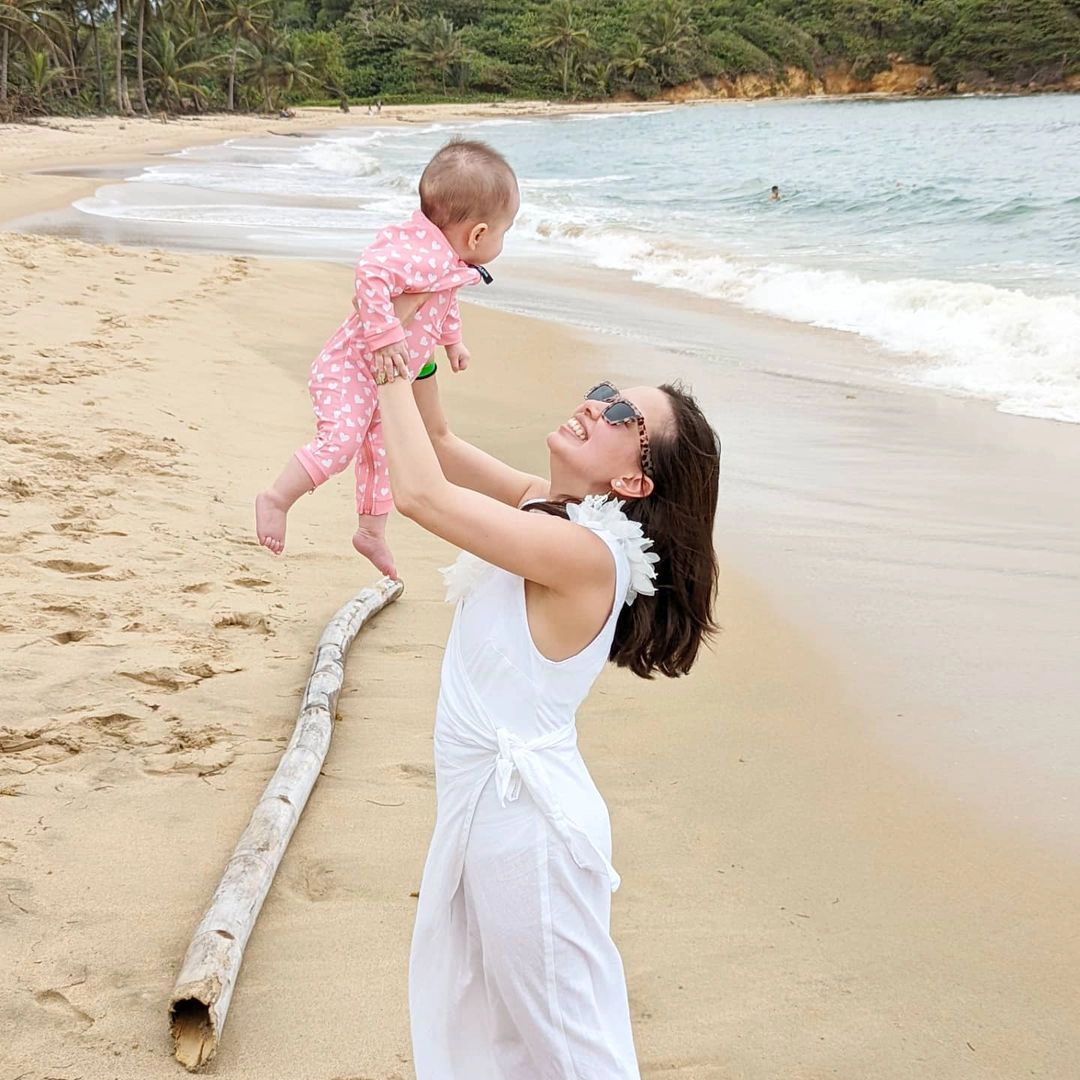 woman holding baby in air on beach