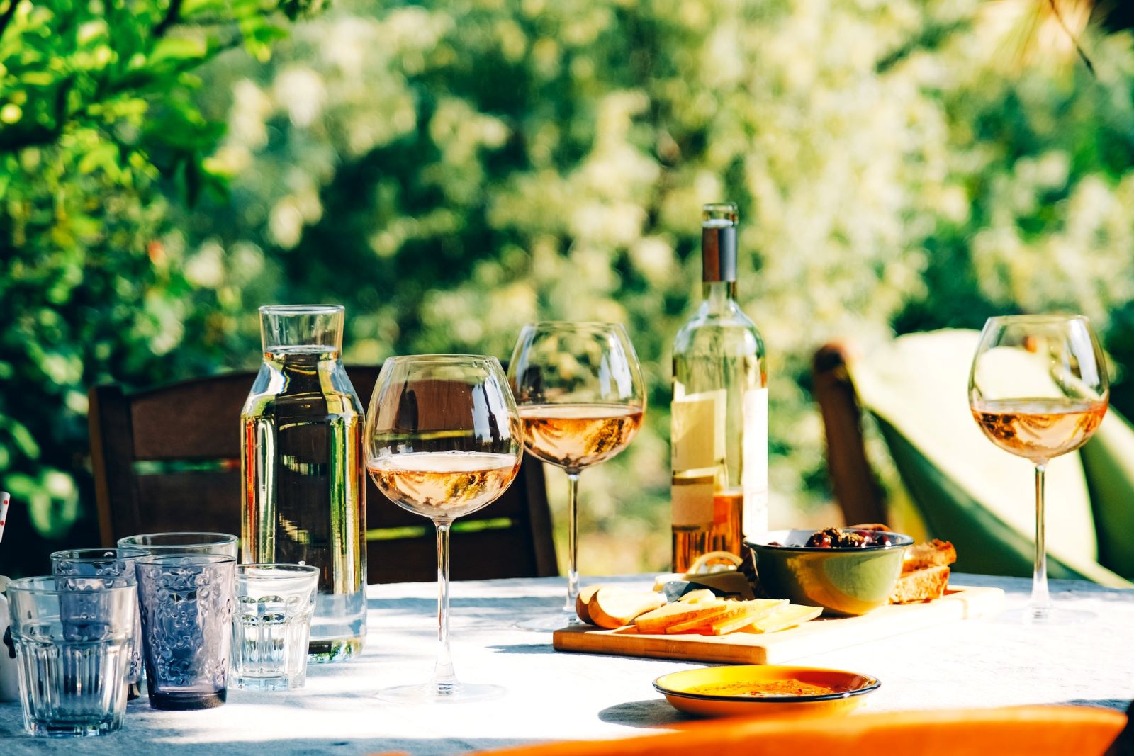 Dinner table with wine glasses, decanter, bottles, and food.