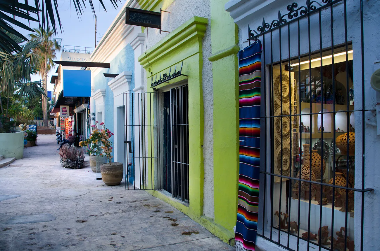 Colorful store fronts and a palm tree-lined sidewalk in San Jose del Cabo