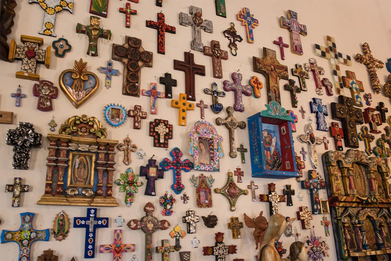 A wall filled with colorful crosses and other religious artifacts