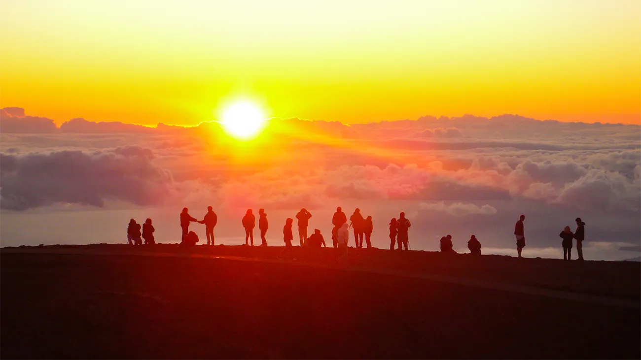 People silhouetted in the distance against a fiery sunset