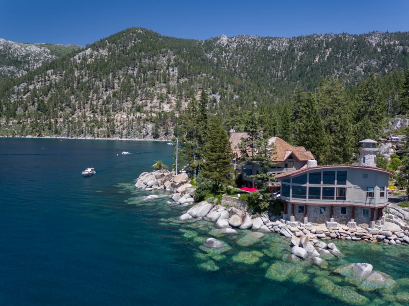 Thunderbird Lodge perched on a rocky shoreline of Lake Tahoe, surrounded by pine trees and overlooking the lake’s clear blue water