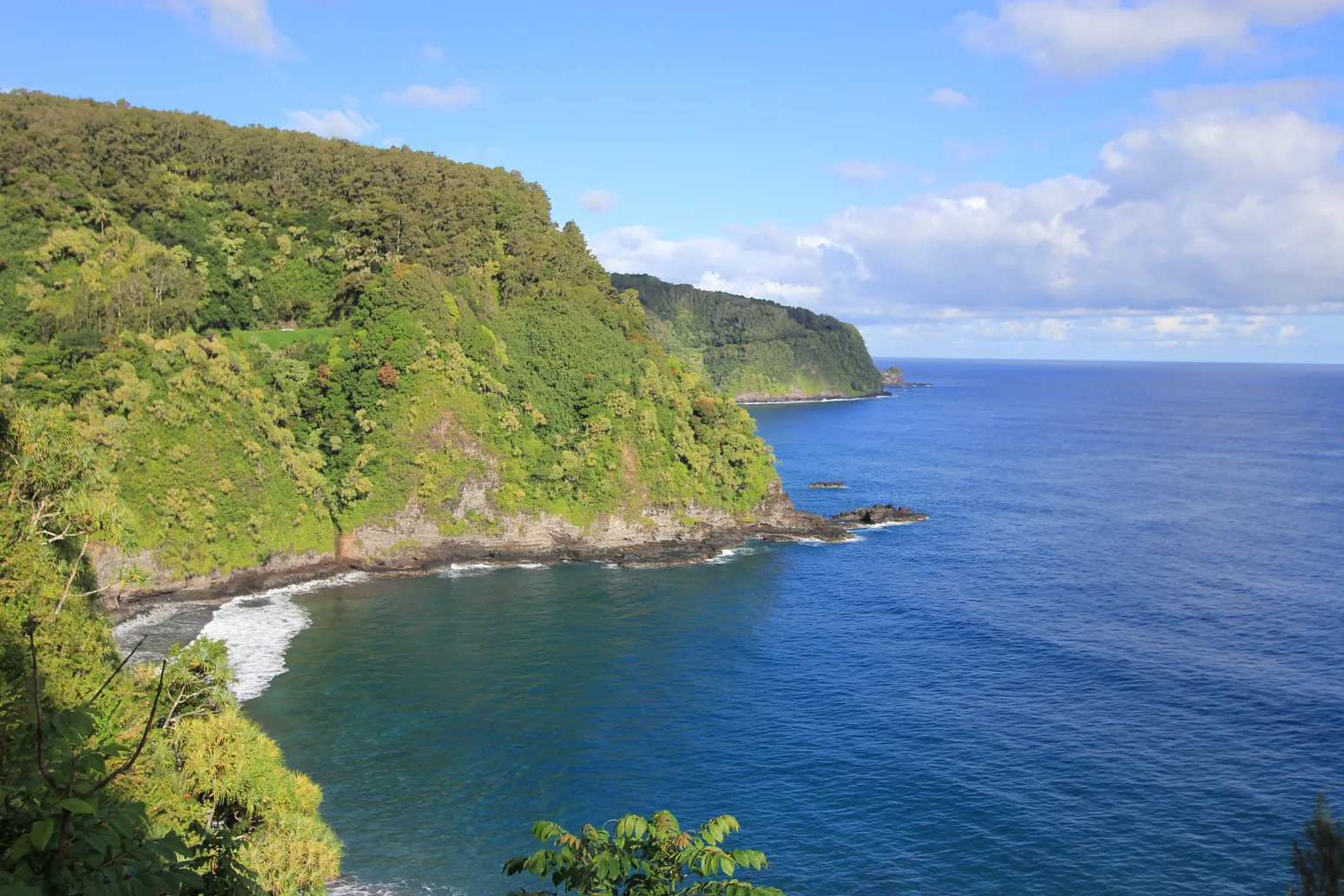 Scenic view of the Road to Hana with green cliffs and ocean below.
