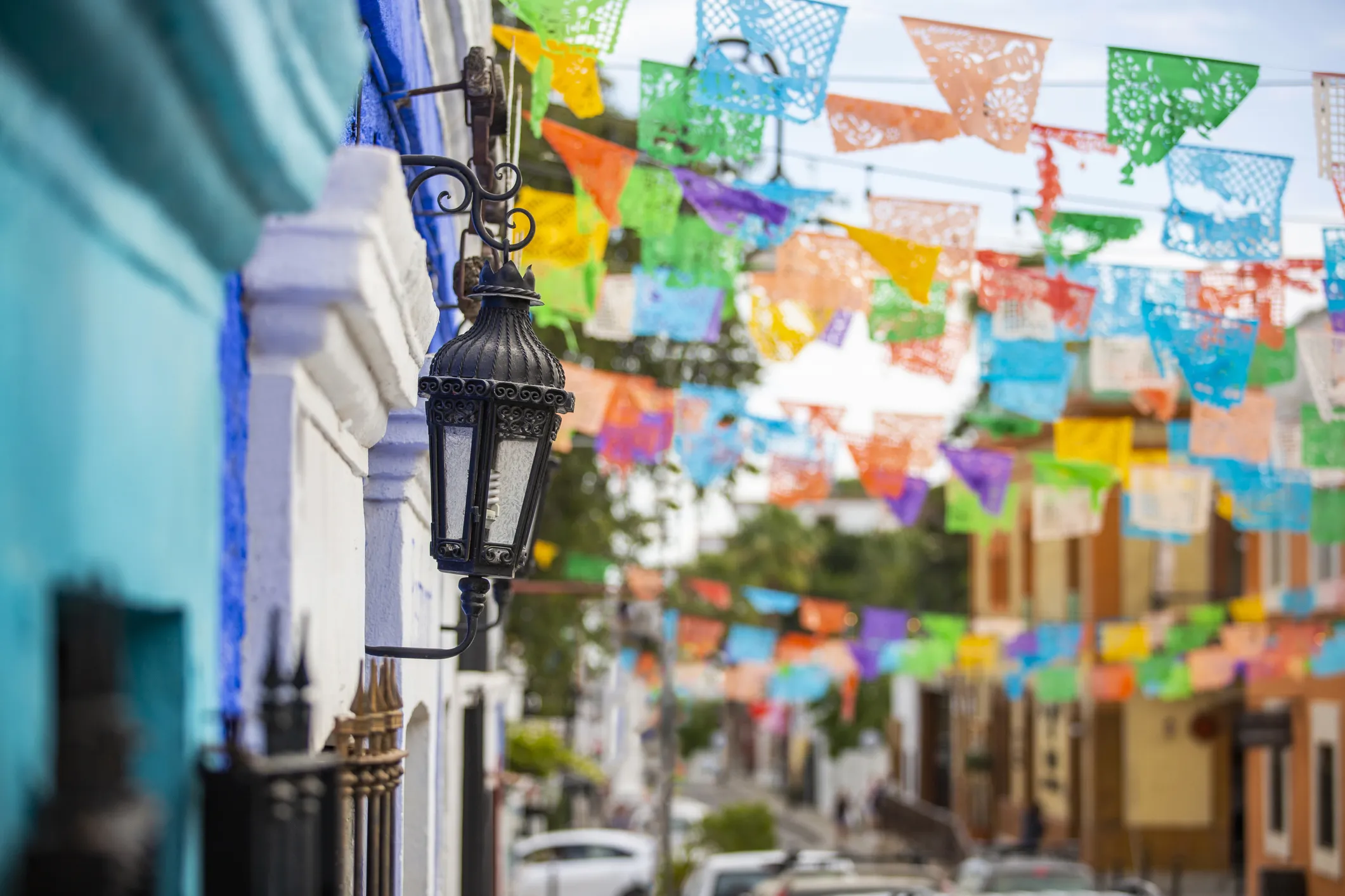Festive street in San José del Cabo with hanging flags, outdoor seating, and shops.