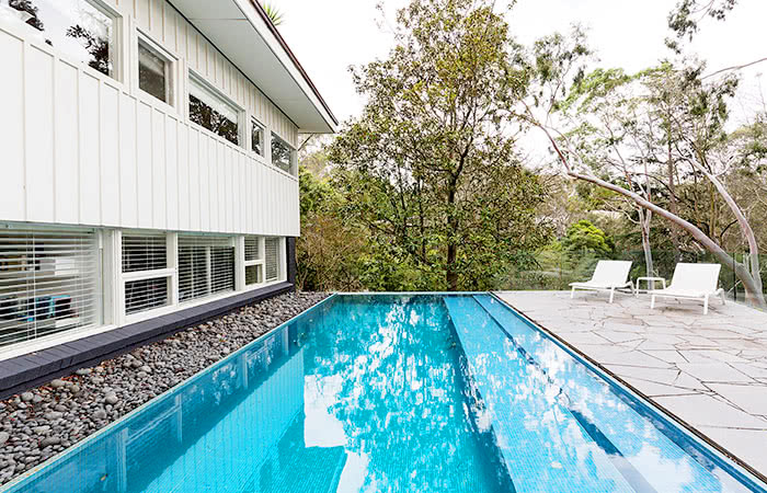 White Mid-century modern home in Palm Springs with a long glistening blue pool accentuating the design.