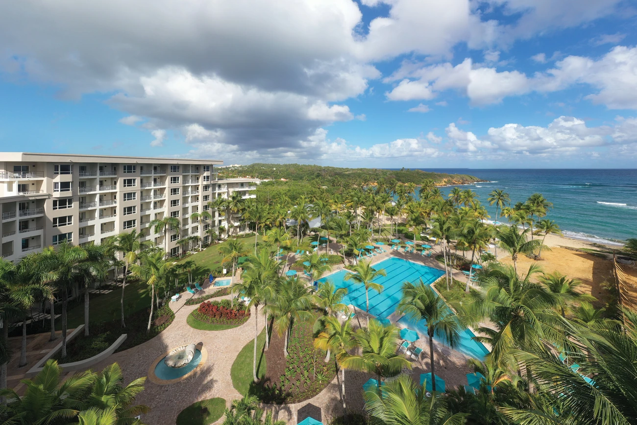 An aerial view of Hacienda del Mar resort area with multiple buildings, swimming pools, and palm trees near the coastline