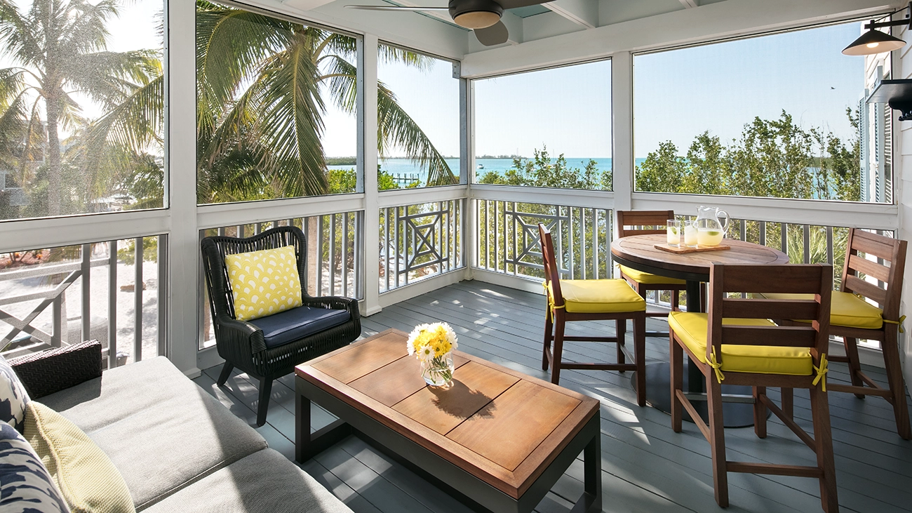 White sand sits outside an outdoor patio with a dining table and couch