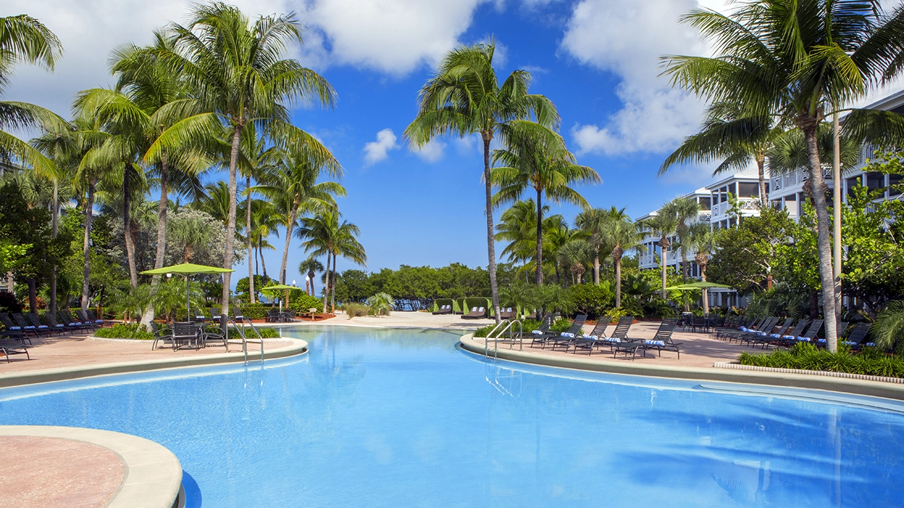 The large swimming pool of the Key West Beach House is surrounded by seating and greenery