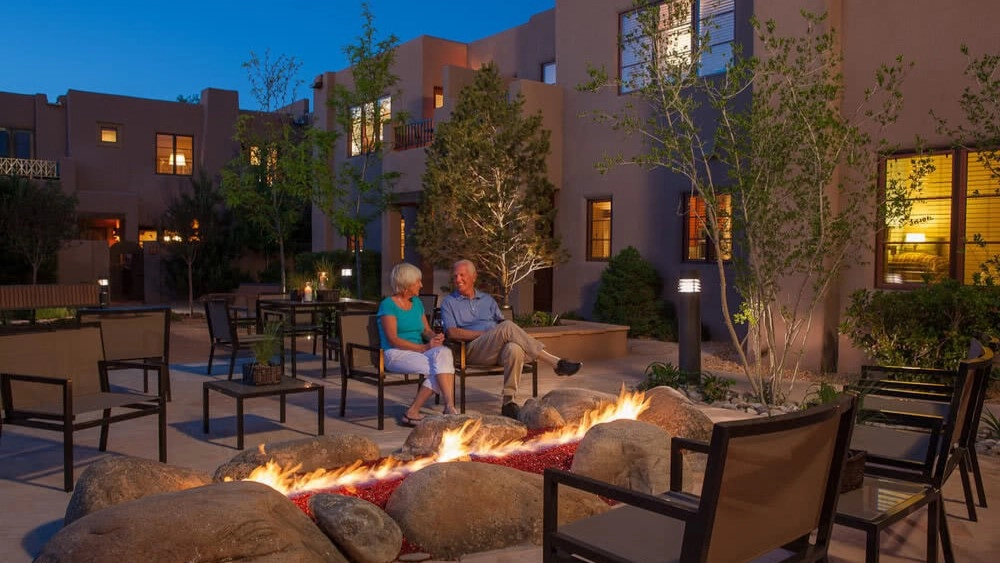A couple warm up next to an outdoor firepit as the sun sets