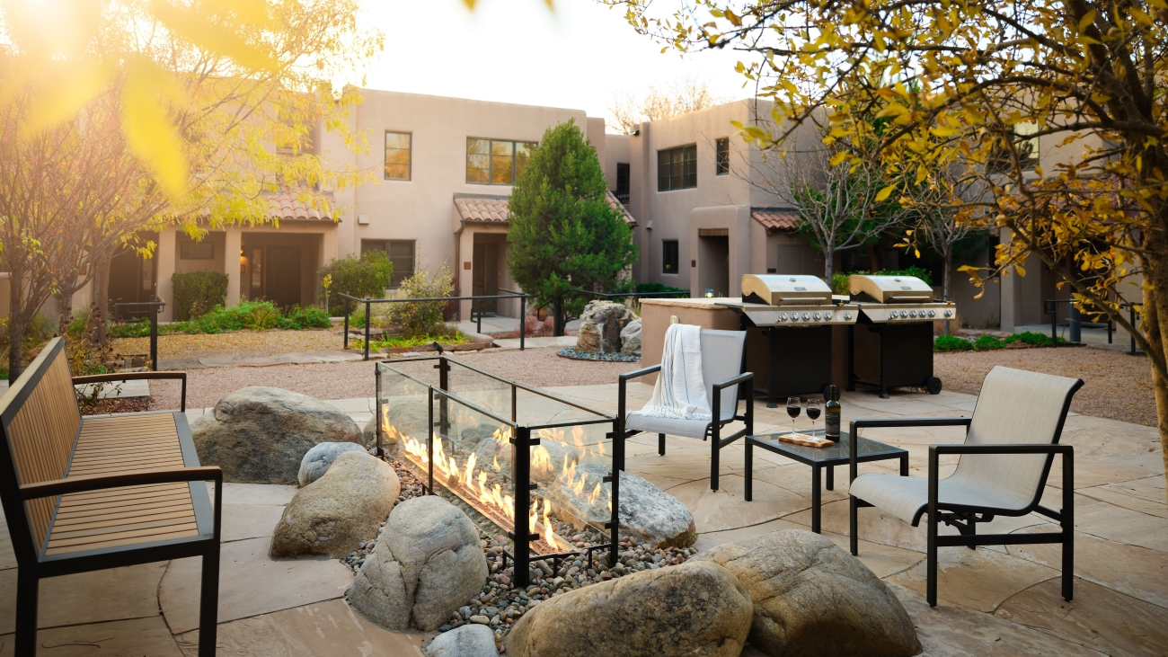 Stone patio with fireplace, grill, benches, and chairs