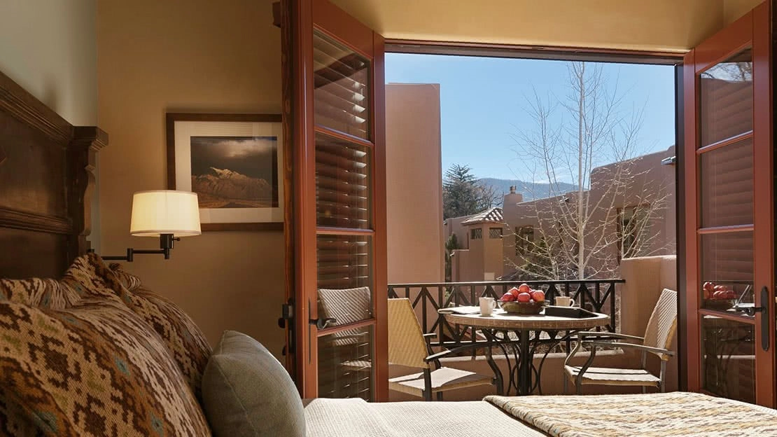 Bedroom with balcony, table, and chairs with a view of the mountains