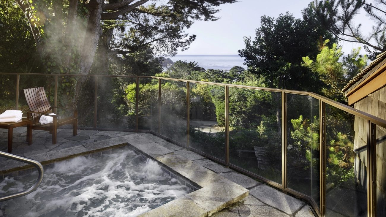 Steam rising from a stone whirlpool spa with chairs and a view of the ocean