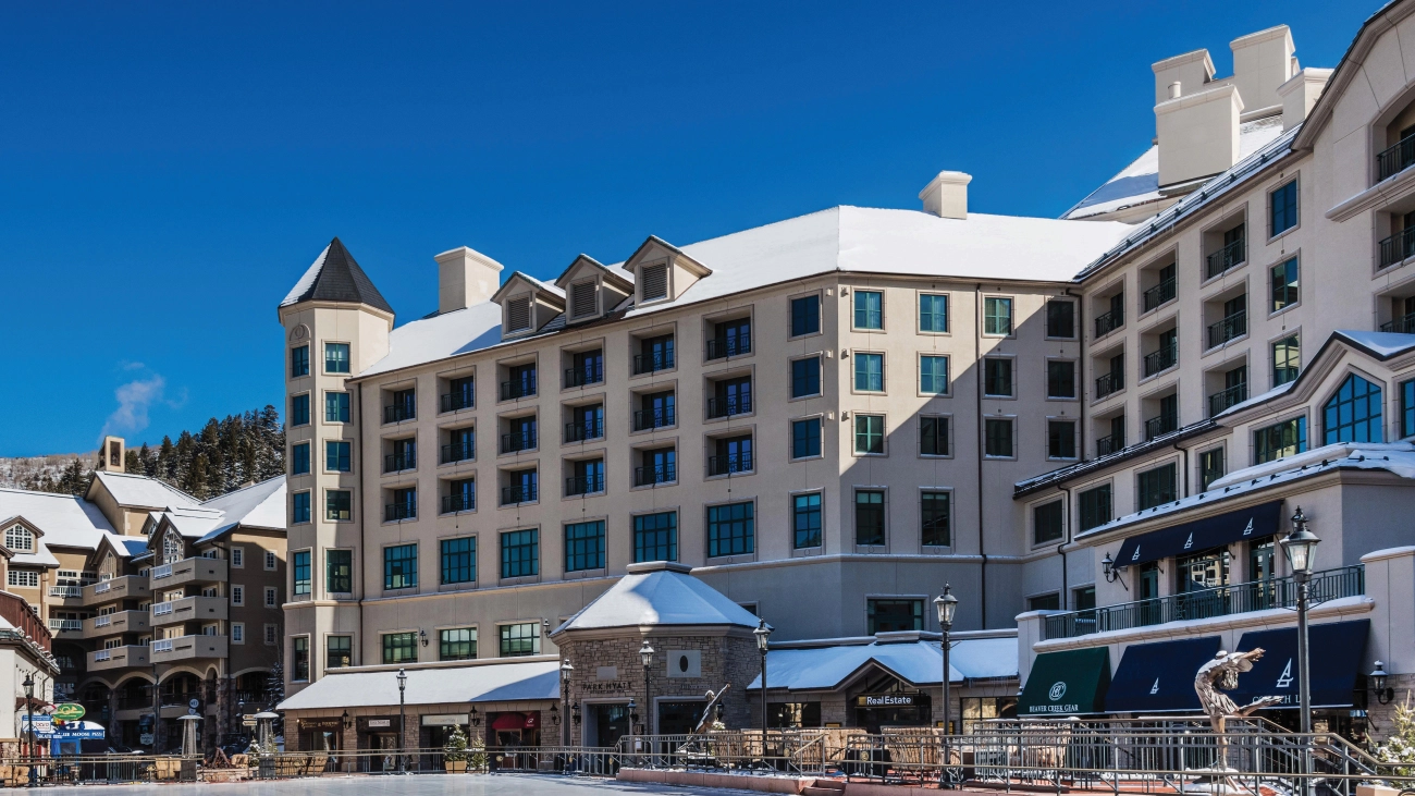 An ice rink sits in front of the resort underneath a blue sky
