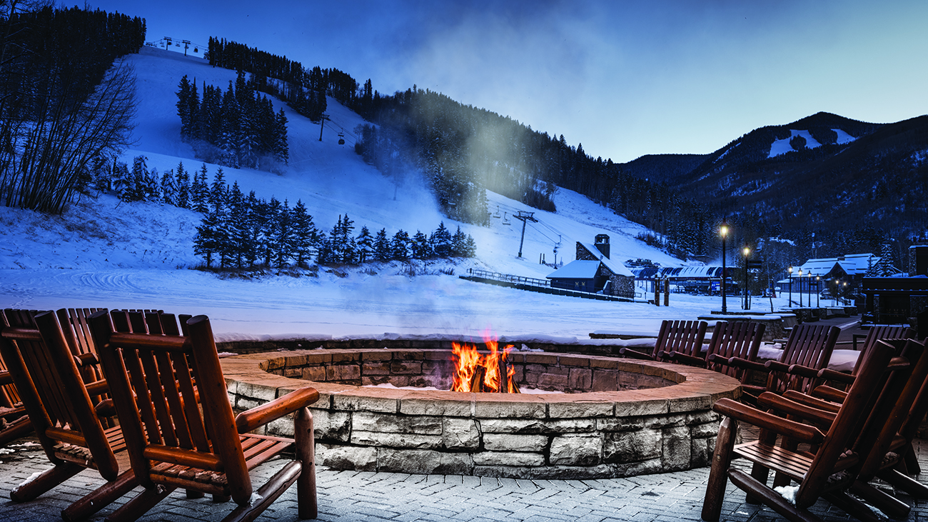 A roaring firepit is lit next to a snow covered hill