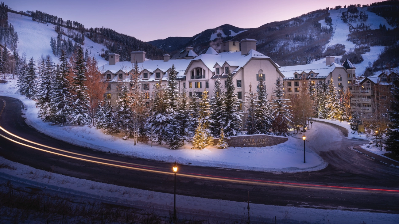 The front entrance of the resort lights up under the sun-setting sky