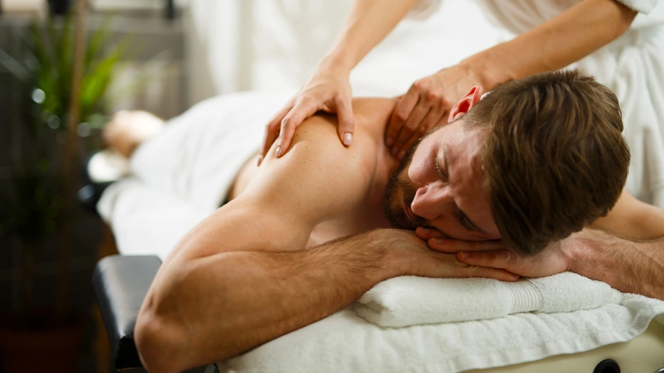 Man in white towel getting a shoulder massage at a spa