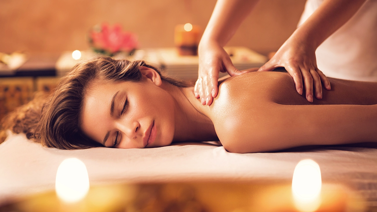 Woman getting a relaxing back massage at a candle-lit spa