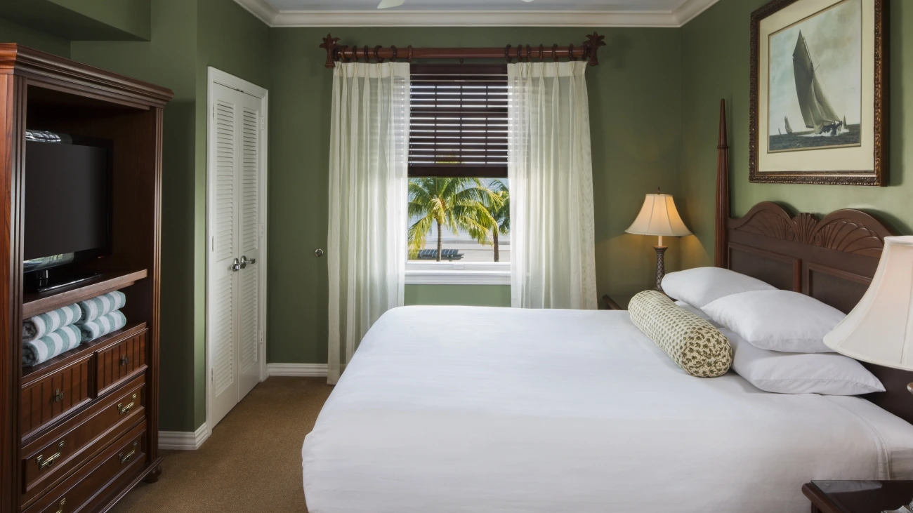 Resort bedroom with view of beach and palm trees