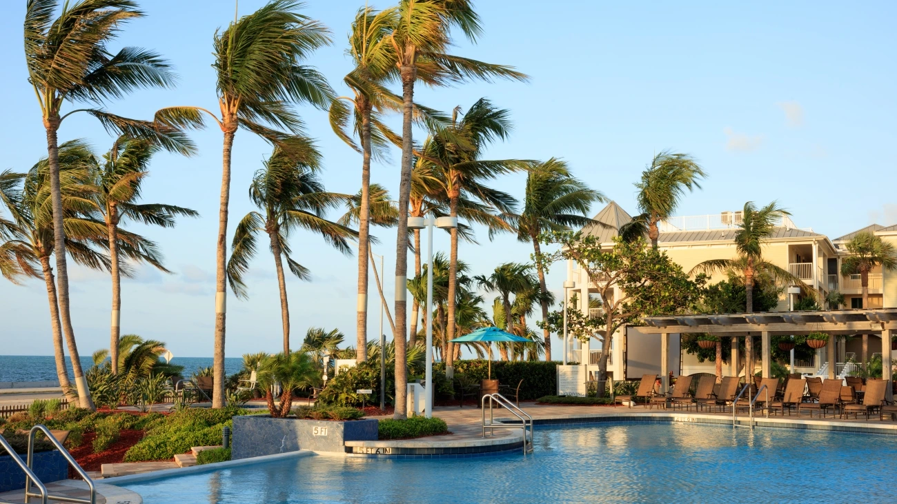Palm trees sway in the breeze beside a shimmering resort pool