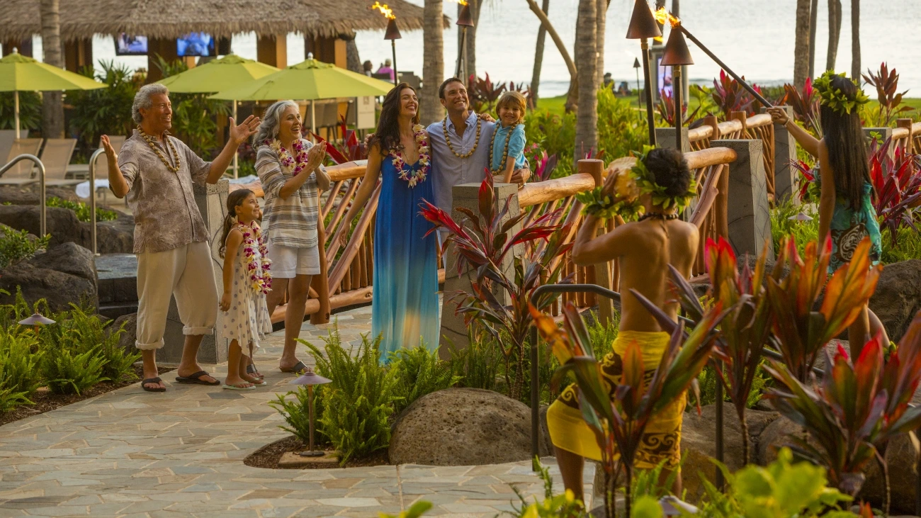Smiling guests watch an authentic torch-lighting ceremony in hawaii