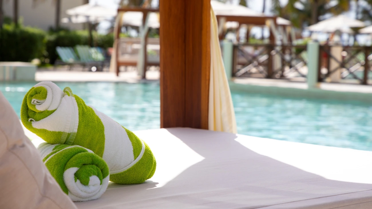 Poolside resort cabana with rolled up green and white beach towels