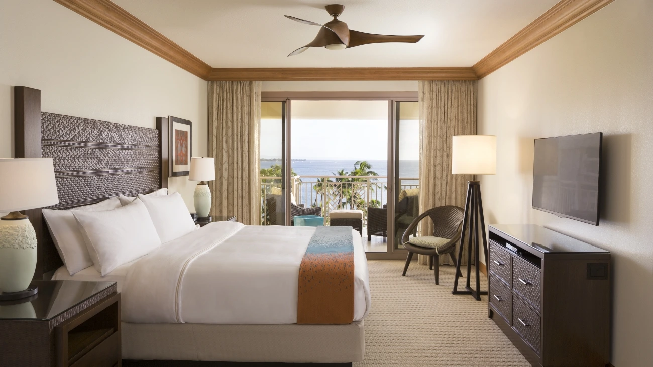 Villa bedroom with patio view of swaying palm trees and the ocean