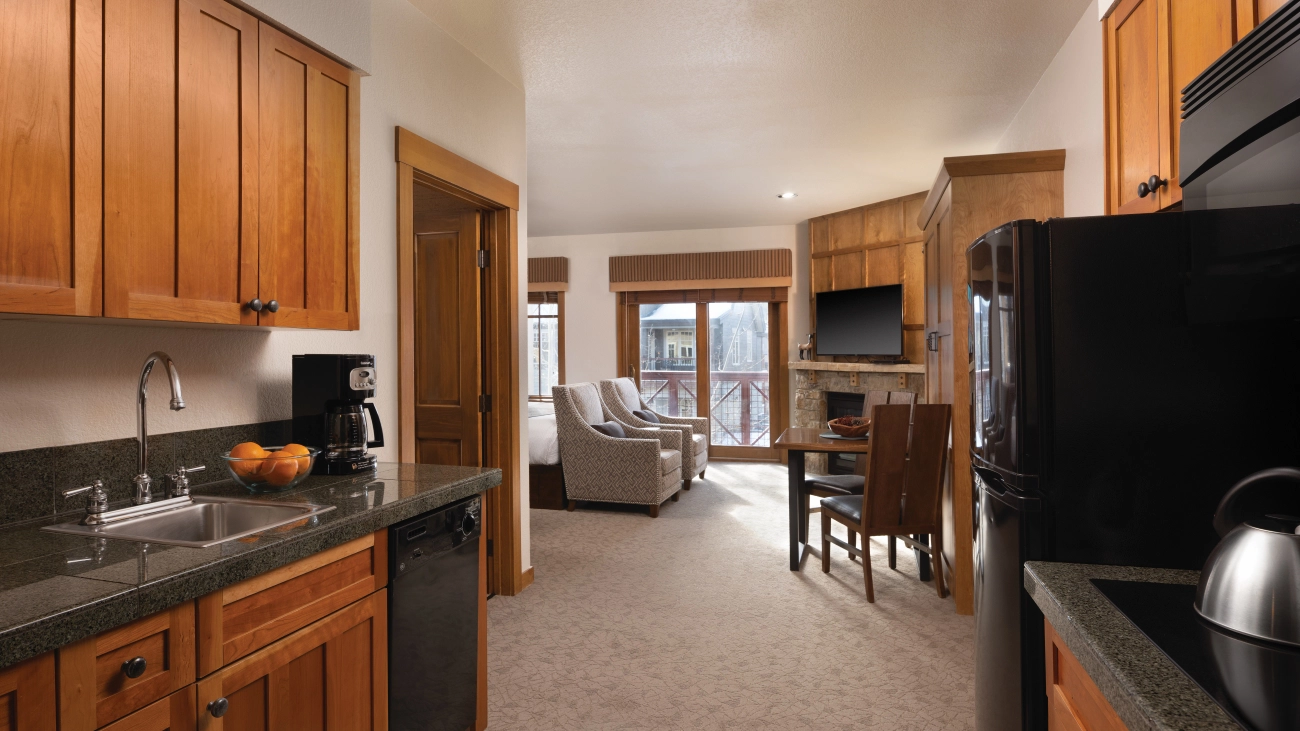 A refrigerator and range lead out to a sitting area with a fireplace and seating