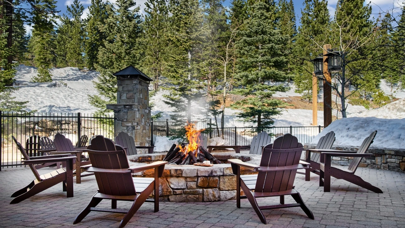 A roaring firepit is lit next to a snow-covered hill
