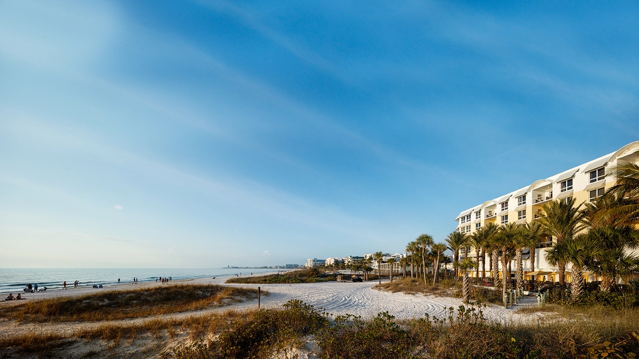A white sand beach sits between the resort and a bright blue ocean