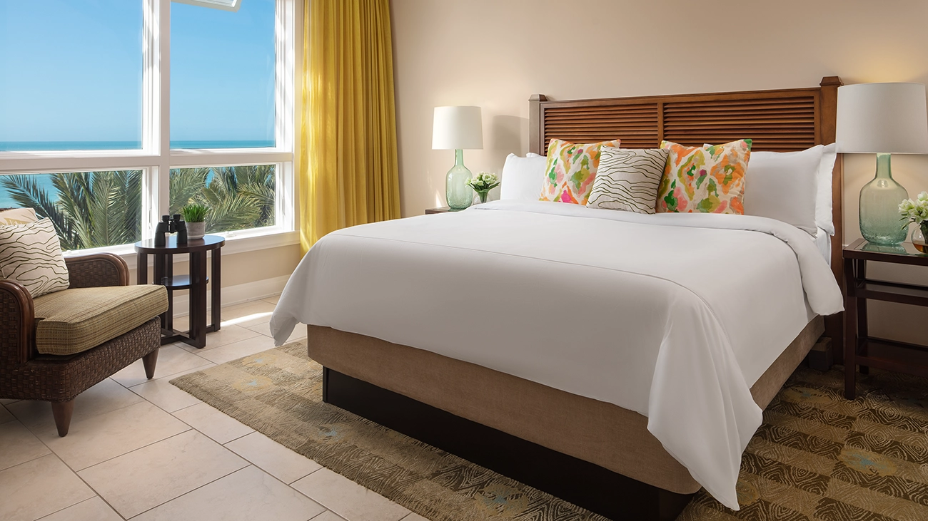 Resort bedroom with view of ocean and palm trees