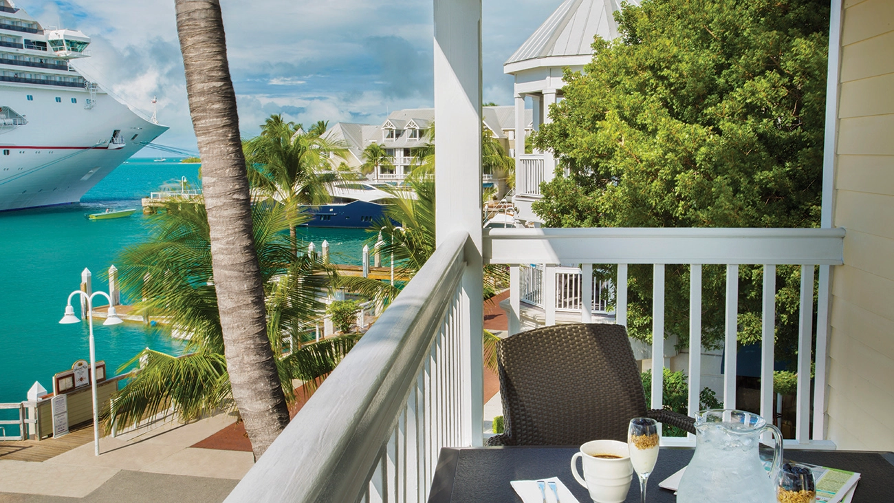 An outdoor patio overlooks a cruise ship parked in the ocean just outside