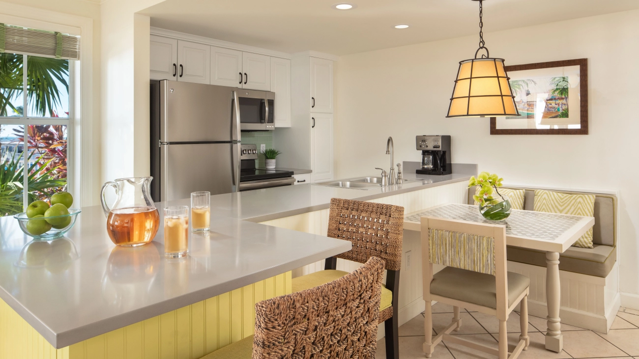 Two glasses and a pitcher of iced tea sit on top of a marble countertop in a villa's fully equipped kitchen