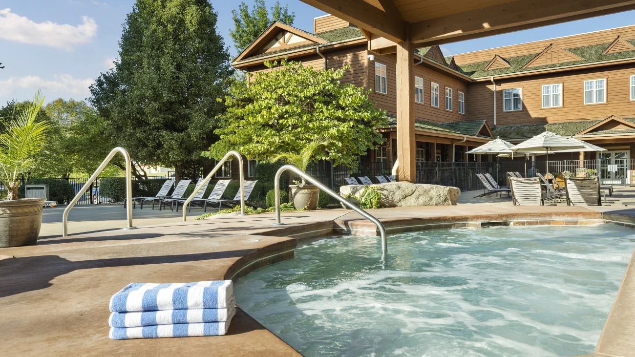 A resort with a whirlpool spa, towels, lounge chairs, and tables