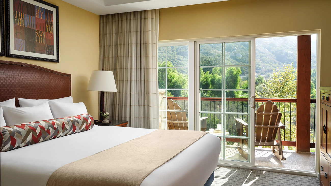 Interior view of villa bedroom with a patio with rocking chairs and a scenic view