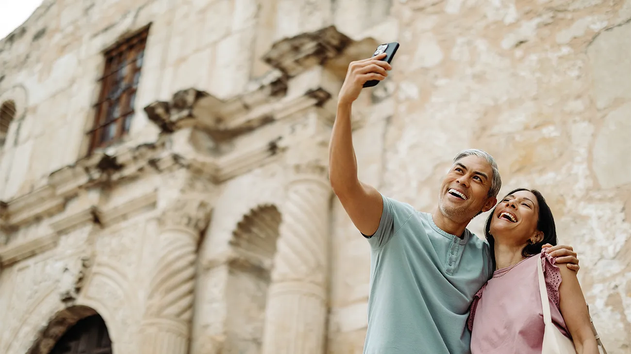 A couple taking a selfie in front of a historic building in San Antonio area
